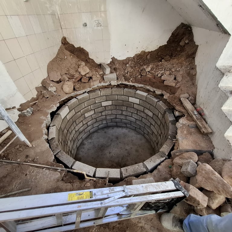 Circular brick well or drainage opening under construction with surrounding dirt and debris, viewed from above