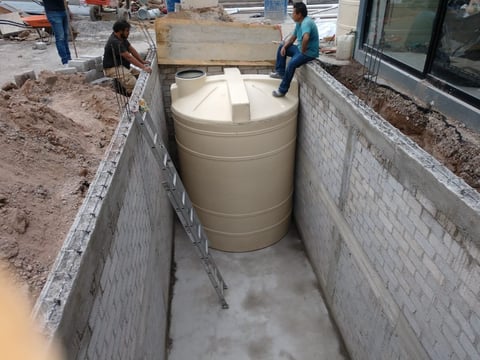 Large cylindrical water tank installed in concrete foundation pit at construction site