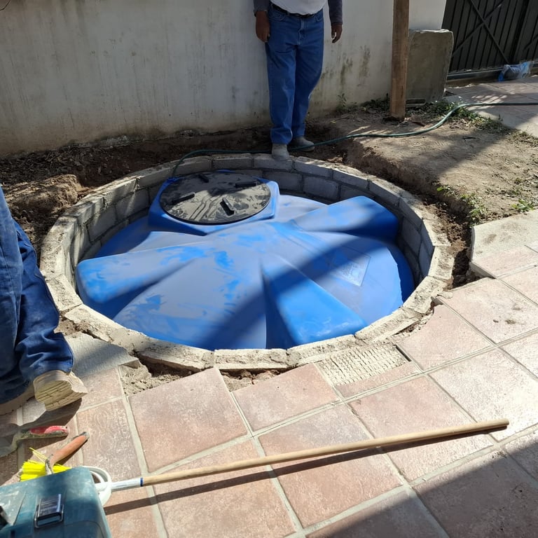 Worker standing over an open circular septic tank or water storage pit with blue plastic lining installed inside
