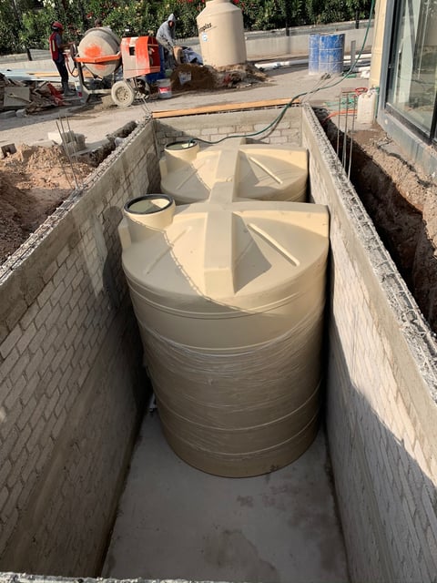 Large cylindrical water tanks installed in concrete pit at construction site
