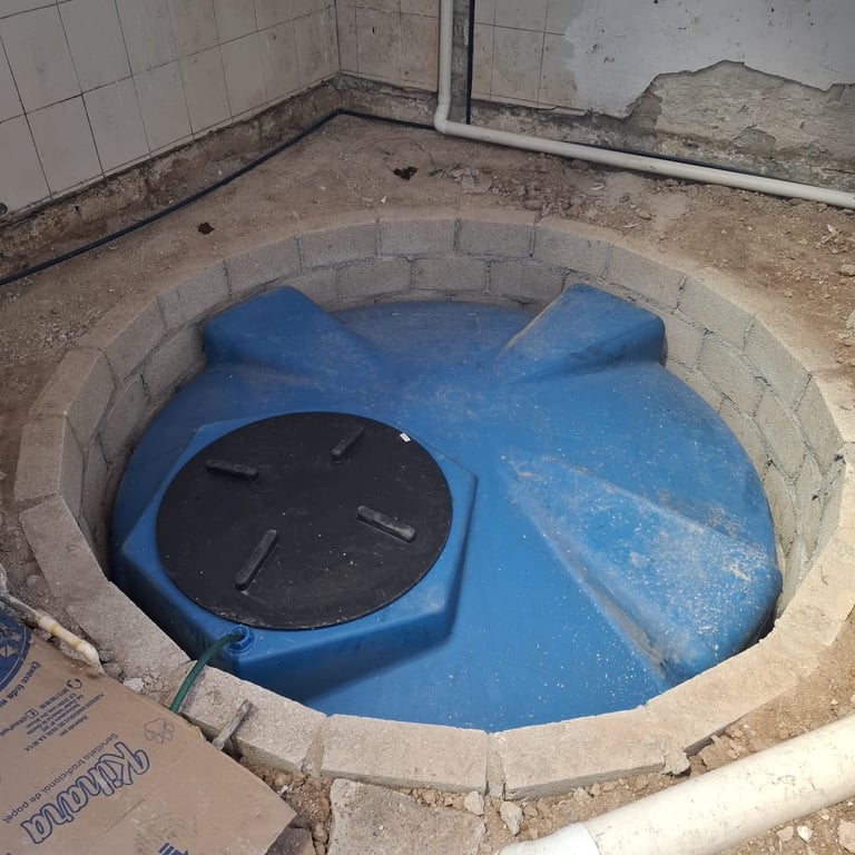 Large blue water tank installed in basement floor with black lid, surrounded by concrete foundation