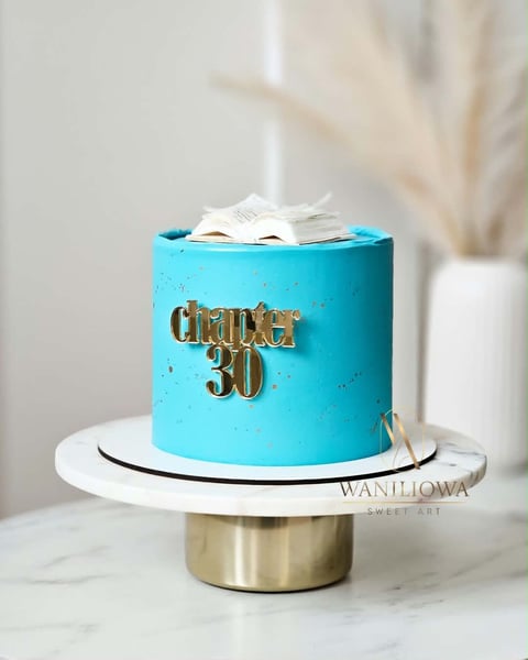 Turquoise birthday cake with gold dance 30 text decoration, white fondant bow on top, displayed on marble surface