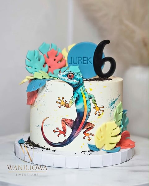 Colorful birthday cake decorated with a rainbow gecko, tropical flowers, and number 6 topper for Jurek celebration