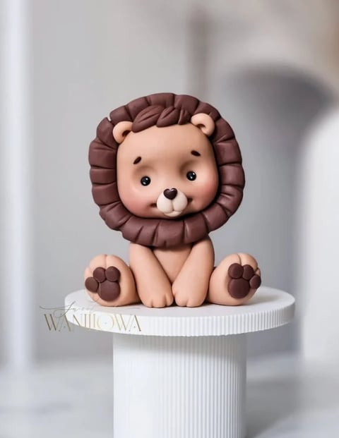 Cute clay lion figurine with brown mane and paws sitting on a white cylindrical pedestal