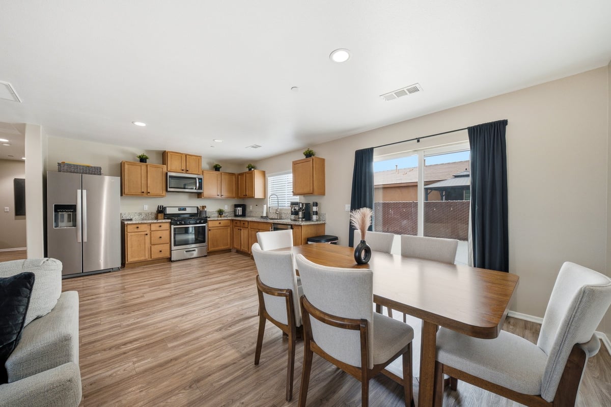 Open concept kitchen and dining area with wood cabinets, stainless steel appliances, and sliding glass doors to patio