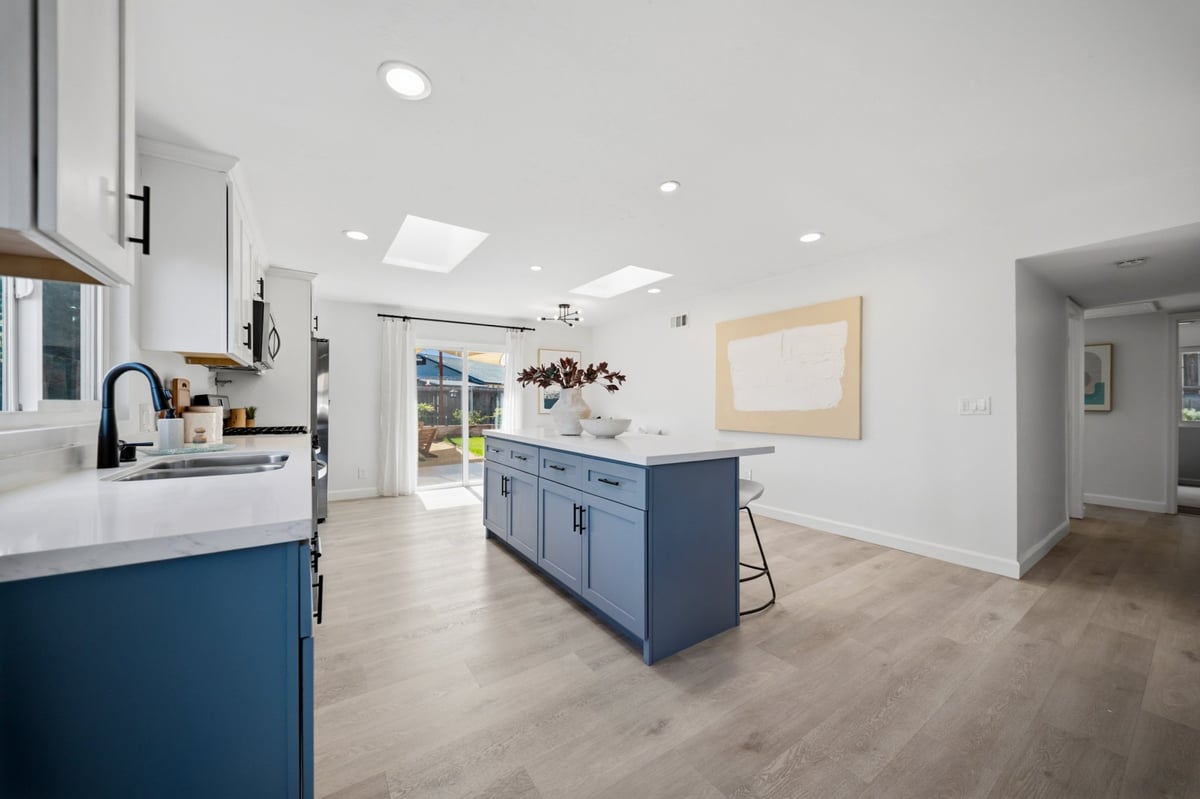 Modern kitchen with blue island and white countertops, recessed lighting, and hardwood flooring