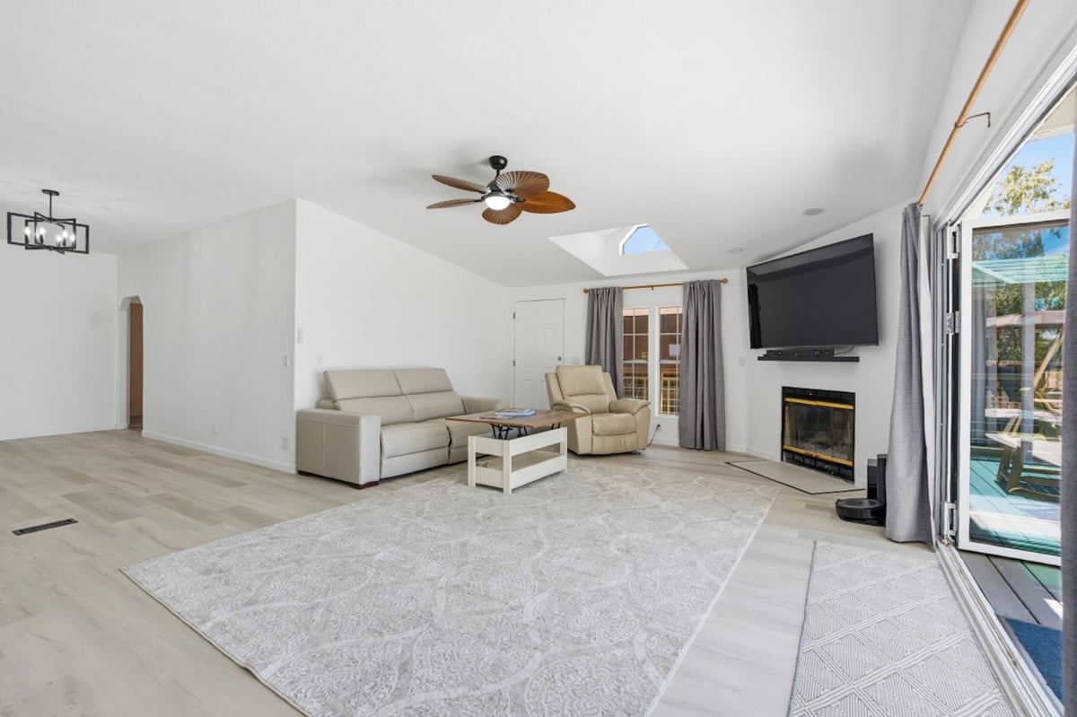Modern living room with sectional sofa, ceiling fan, fireplace, and sliding glass doors opening to patio