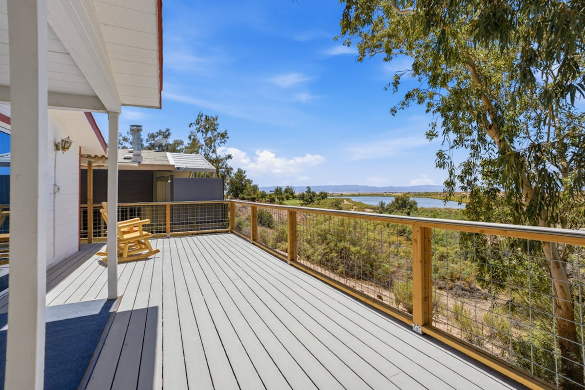 Modern deck with wooden railing overlooking scenic valley landscape on clear sunny day