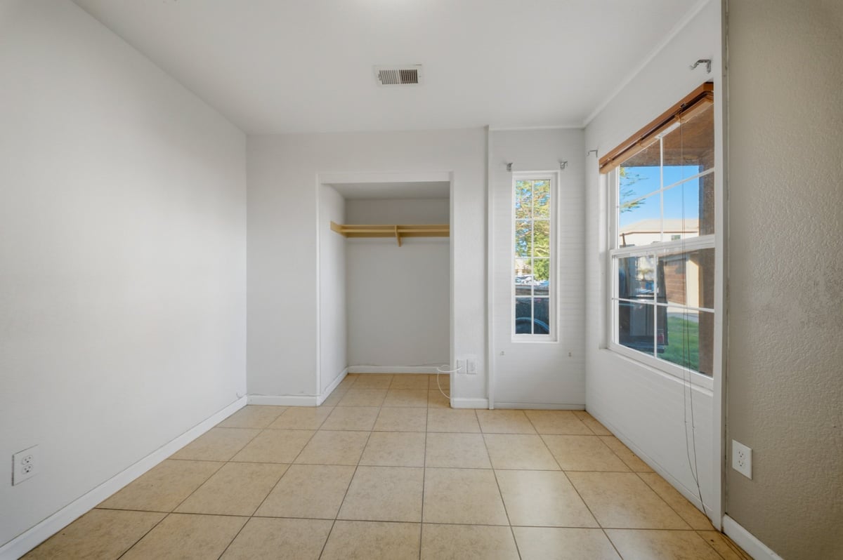 Empty room with tile flooring, open closet, and glass door with natural light from window