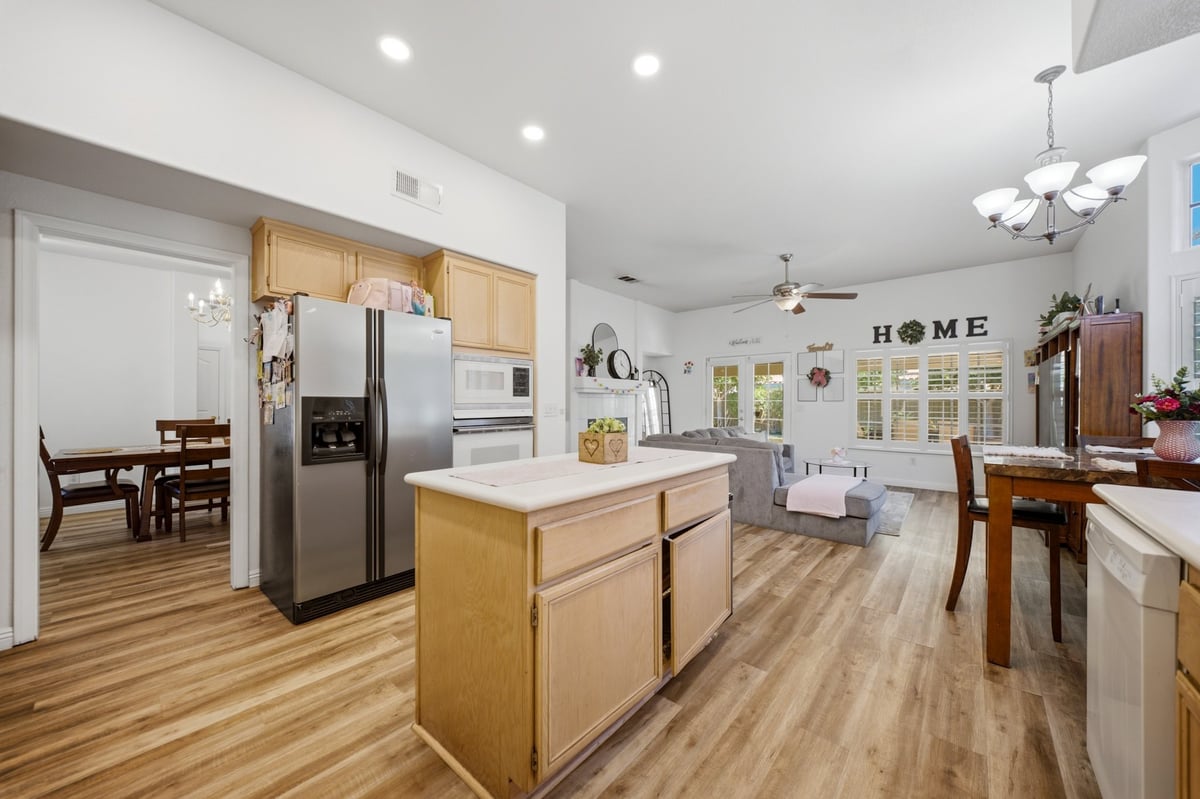 Spacious modern kitchen with wood cabinets, island, stainless steel appliances, and dining area visible in background