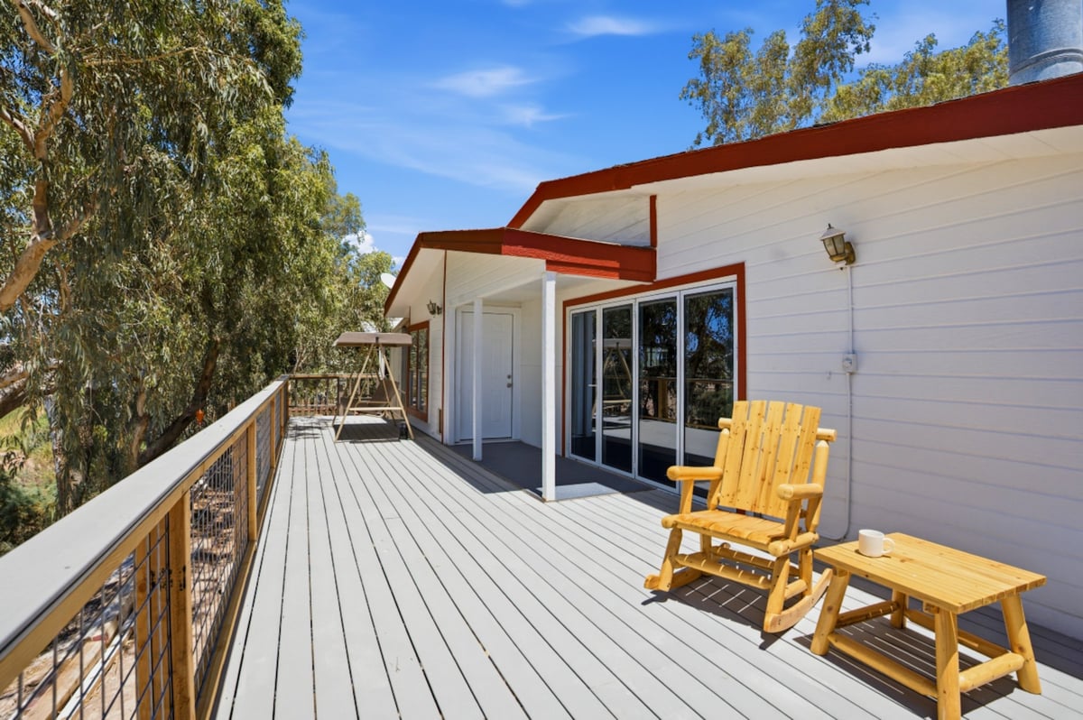 Modern deck with white railings, yellow Adirondack chairs, and a contemporary house with red roof accents