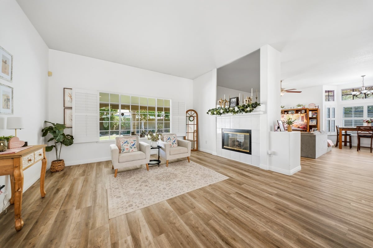 Modern open-concept living room with wood flooring, white walls, fireplace, built-in shelving, and transitional furnishings