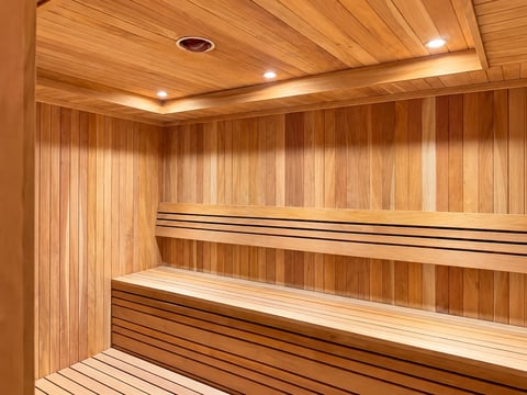 Interior of a wooden sauna with tiered benches and recessed ceiling lights