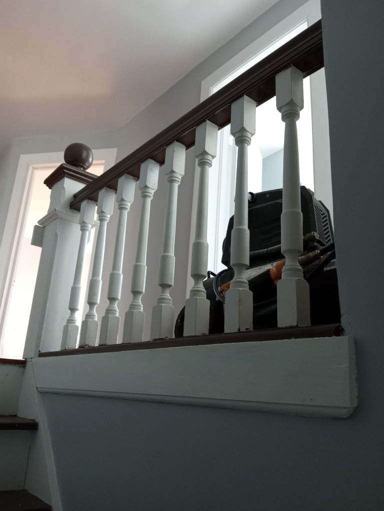 White wooden staircase railings with turned balusters and dark handrail, interior mezzanine area with white walls