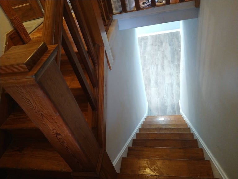 Wooden staircase with bright natural light coming through a window or glass door at the landing above