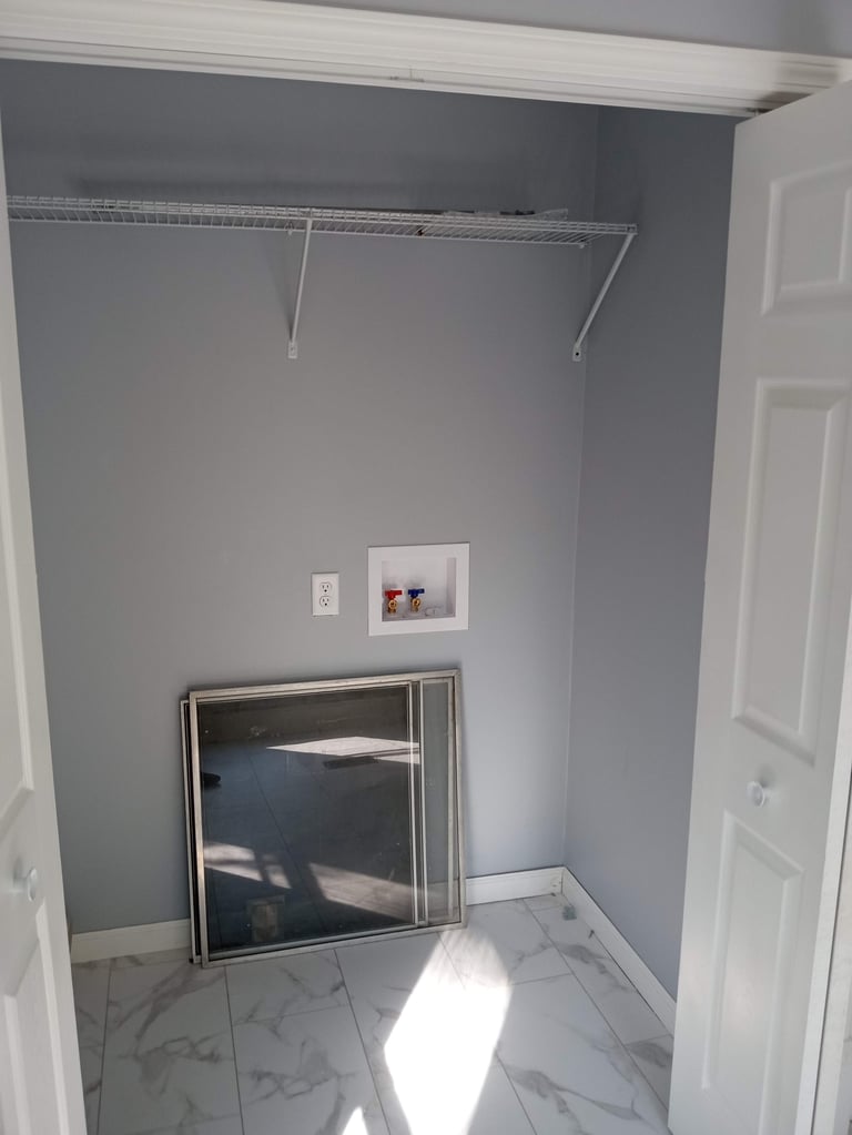 Empty walk-in closet with gray walls, white trim, metal hanging rod, and white tile flooring with sunlight streaming in