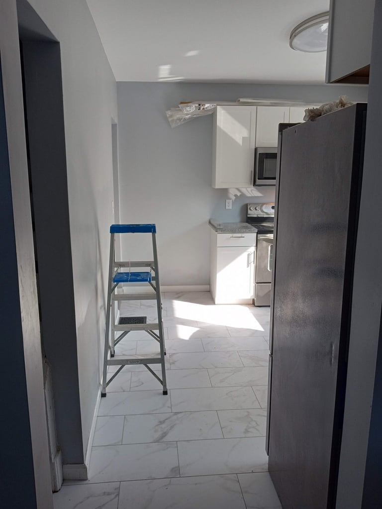 Blue and gray ladder in renovated kitchen with white tile flooring and stainless steel appliances