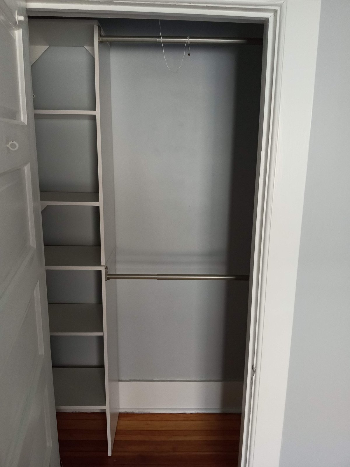 Empty walk-in closet with built-in shelving units on left side and double hanging rod