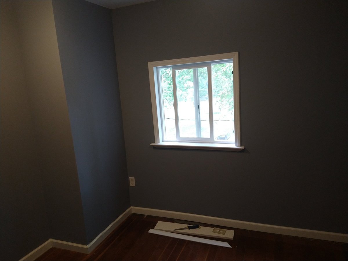 Empty room with dark walls, wooden flooring, and a multi-pane window with natural light