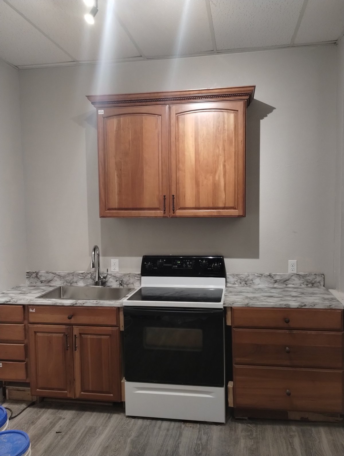 Kitchen with marble countertops, wood cabinets, black and stainless steel range, and wall-mounted wooden cabinet above sink