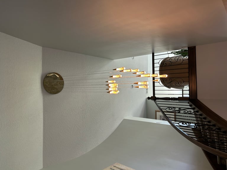 Modern bedroom with white brick walls, a round mirror on the left, and a black bed frame with brass pendant lights above it.