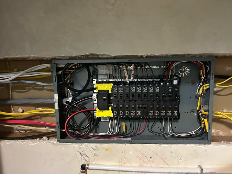 Open electrical panel showing circuit breakers, wiring, and yellow safety ties mounted on a wall
