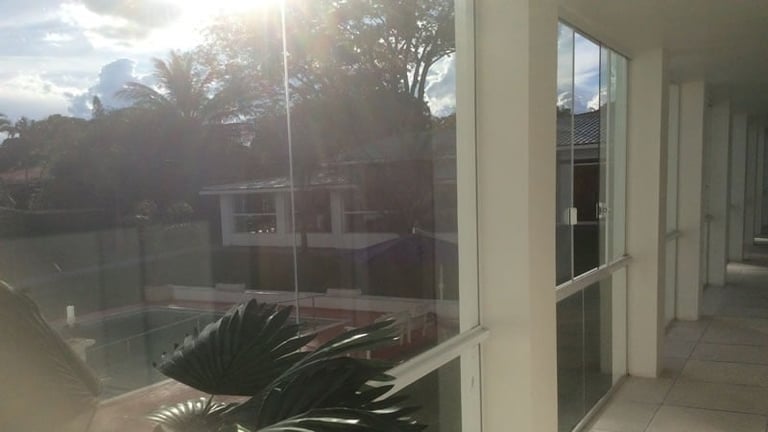 Modern building exterior with glass windows and doors overlooking a courtyard with palm trees and lawn