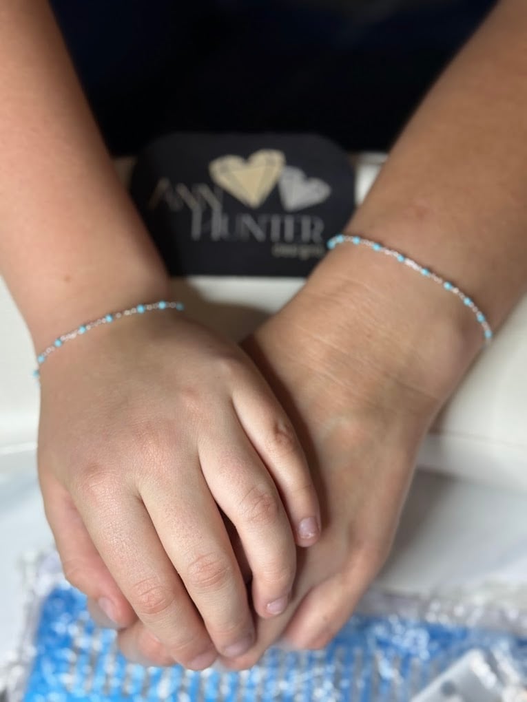 Two people holding hands wearing beaded bracelets, showing affection and connection
