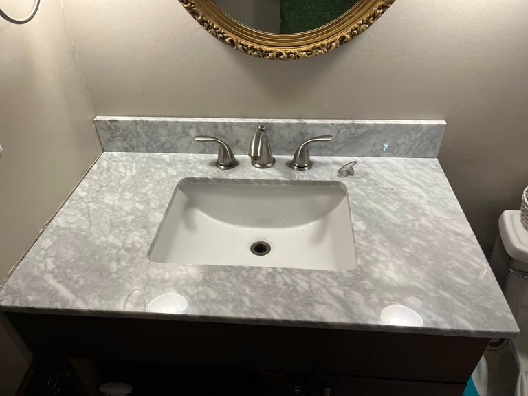 Bathroom sink with white marble countertop, undermount ceramic basin and chrome faucet