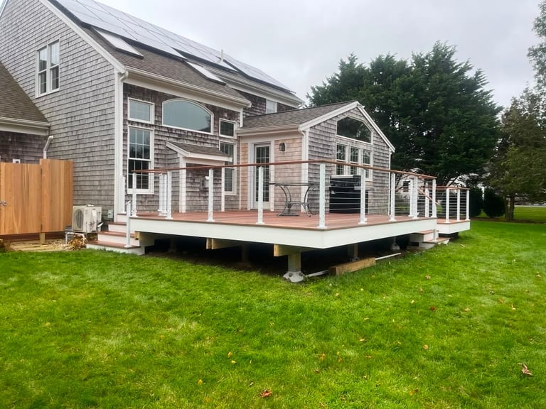 Modern cottage-style house with wooden deck and large windows set on manicured lawn