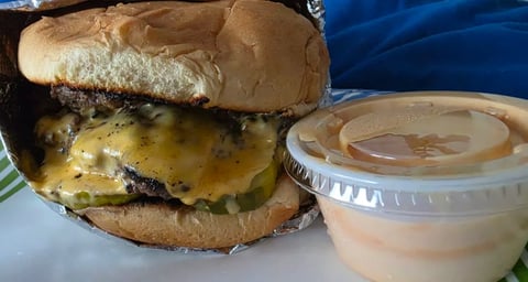 Cheeseburger with melted cheese and caramelized onions served with golden french fries and ketchup