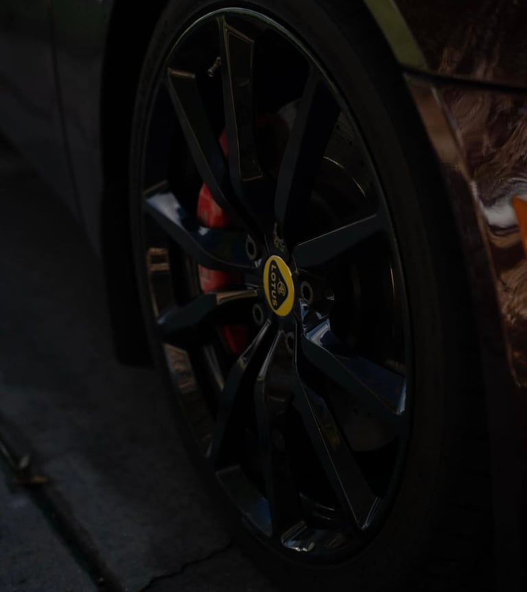 Close-up of a black sports car wheel with yellow center cap and red brake calipers visible