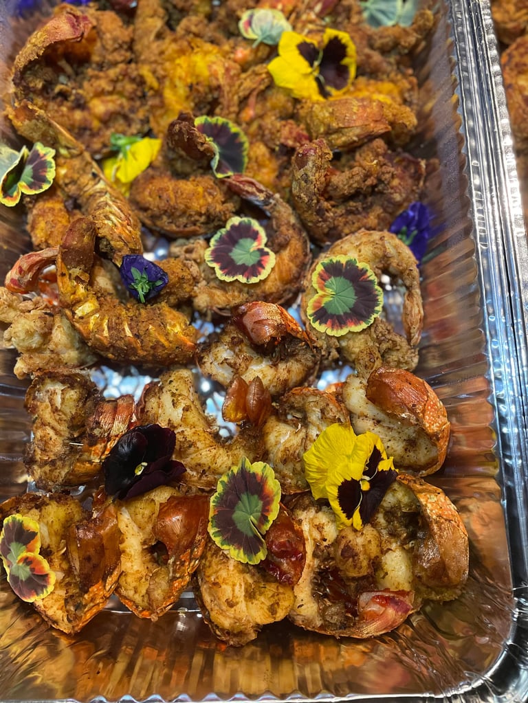 Golden-brown fried chicken pieces garnished with colorful edible flowers on a wooden serving board