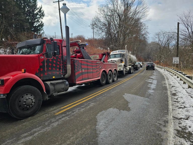 Red fire truck parked on wet highway with other vehicles and bare trees in background