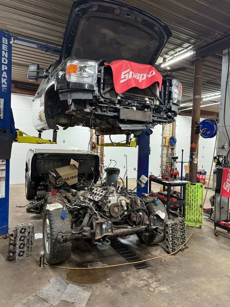 Car lifted on hydraulic lift in auto repair shop with engine and components removed for maintenance