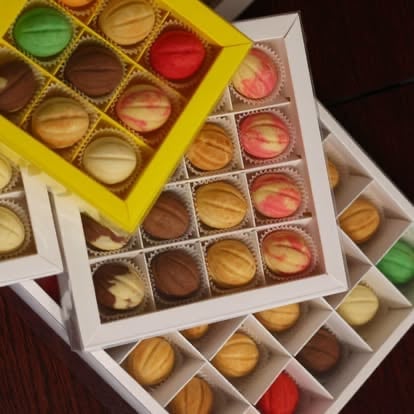 Assorted chocolates and candies in colorful gift boxes with various flavors and colors arranged on a dark surface