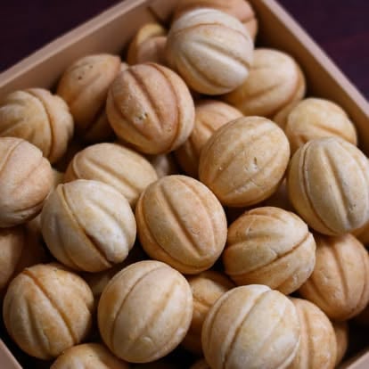 Cardboard box filled with golden-brown oval-shaped cookies with ridged texture patterns