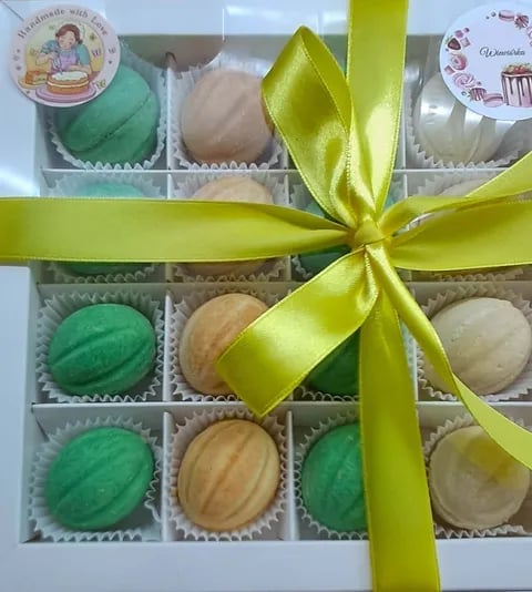 Assorted handmade truffles and chocolates in a gift box with yellow ribbon bow and decorative labels