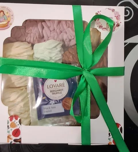 Gift box containing assorted chocolates and Lovare bergamot truffle black tea tied with a green ribbon