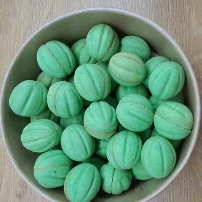 Bowl of fresh green melons with ridged skin arranged on a wooden surface