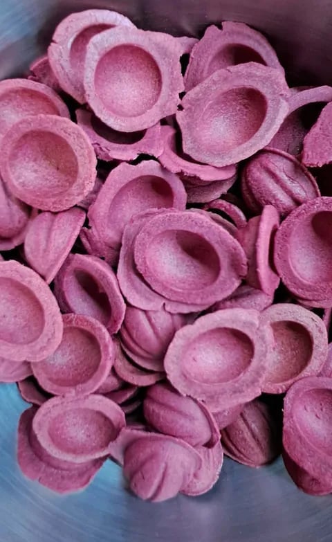 Pink foam egg carton cups stacked together in a pile, viewed from above