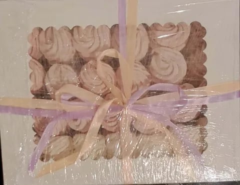 Decorative wooden carved ornaments wrapped in clear cellophane with a lavender ribbon bow
