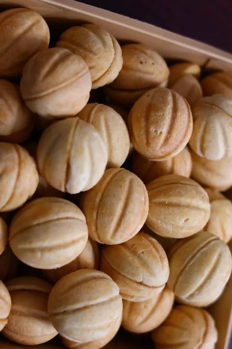 A box filled with round, golden-brown melon pan or bread rolls with ridged patterns on their surface