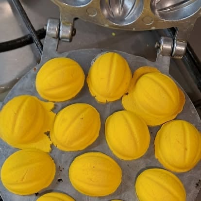 Yellow melon-shaped molds in a metal mold tray with industrial equipment visible at top