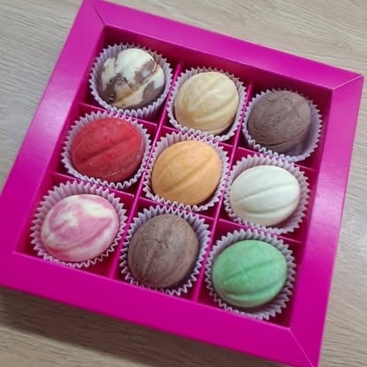 Assorted macarons in a pink gift box with nine colorful French cookies in various flavors arranged in rows