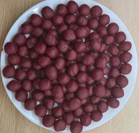 Overhead view of numerous red grapes arranged on a white plate on a wooden surface