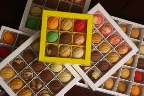 Assorted chocolate truffles and pralines arranged in decorative boxes, with a yellow box prominently featured in the center