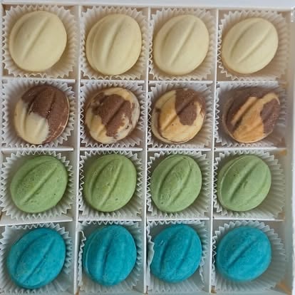 Grid of 16 colorful iced cookies showing four rows with white, brown, green, and teal frosting varieties