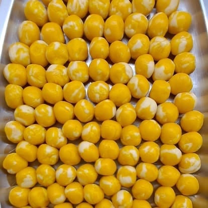Overhead view of golden yellow round loquat or longan fruits arranged in a white tray