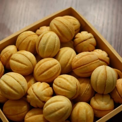 Golden walnut-shaped butter cookies arranged in a cardboard box